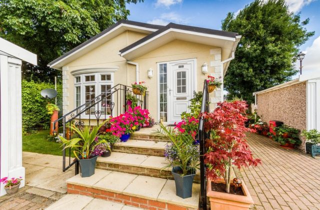 The front steps, decorated with potted flowers, leading to the door of a newly built residential park home
