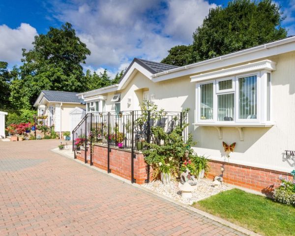 A long driveway leading to two residential park homes and a garage