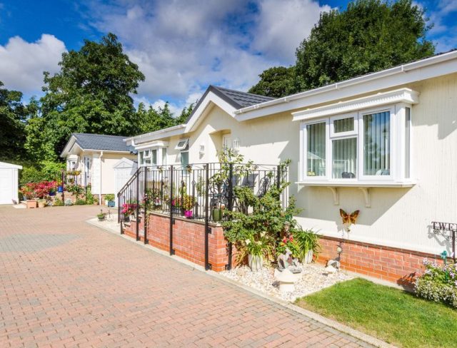 A long driveway leading to two residential park homes and a garage