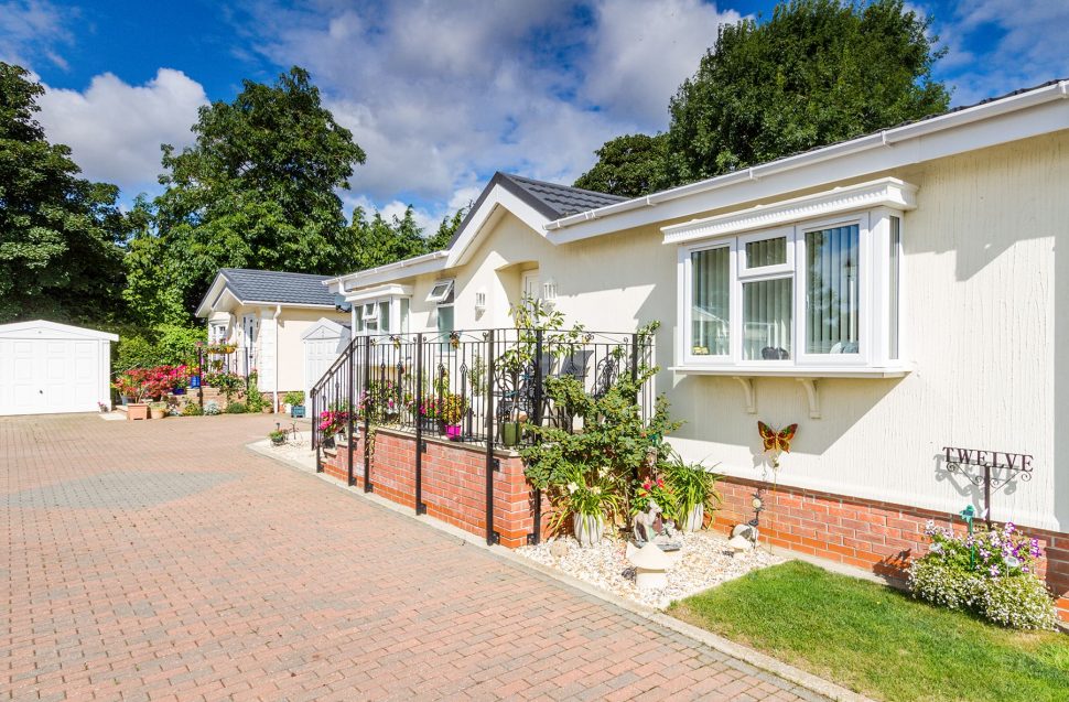 A long driveway leading to two residential park homes and a garage