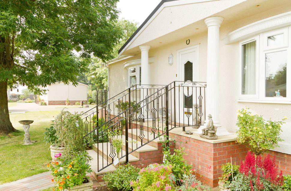 The front of a park home with stairs leading up to the front door and porch area